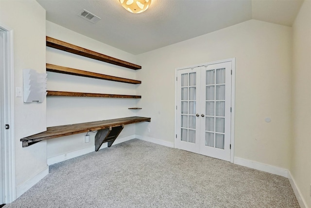 unfurnished office with french doors, visible vents, baseboards, lofted ceiling, and carpet