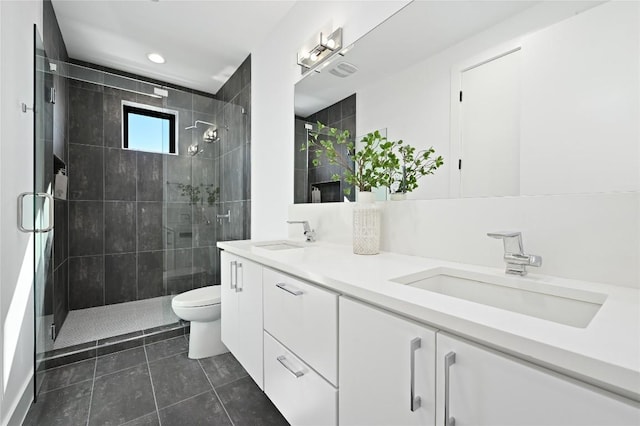 bathroom featuring double vanity, a sink, a stall shower, and toilet