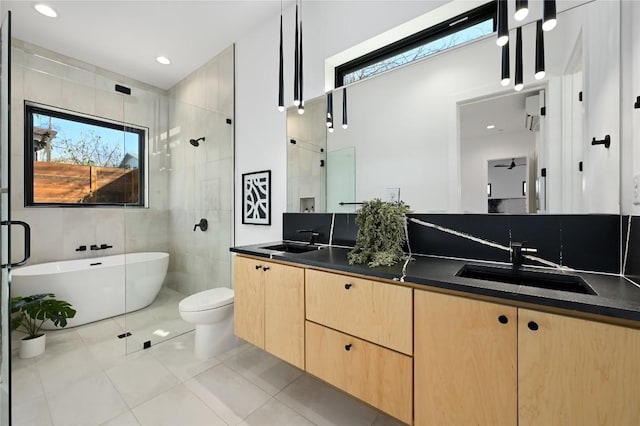 full bath featuring double vanity, a sink, a freestanding tub, and a tile shower