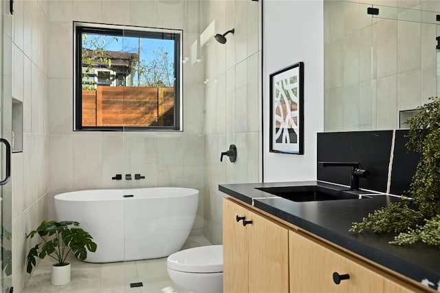 full bath with a freestanding bath, tile patterned flooring, vanity, toilet, and tile walls