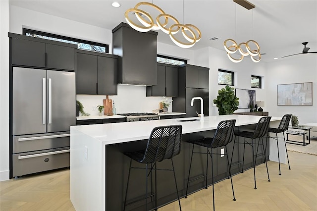 kitchen featuring freestanding refrigerator, recessed lighting, light countertops, dark cabinets, and a sink