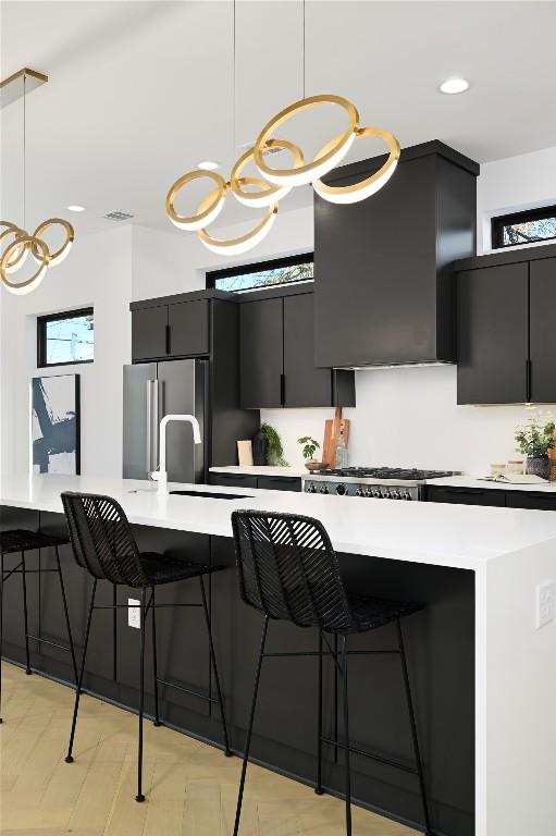 kitchen with an inviting chandelier, dark cabinets, a sink, appliances with stainless steel finishes, and decorative light fixtures