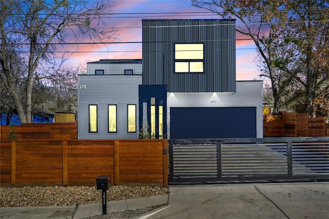 modern home with a garage, a gate, a fenced front yard, and driveway