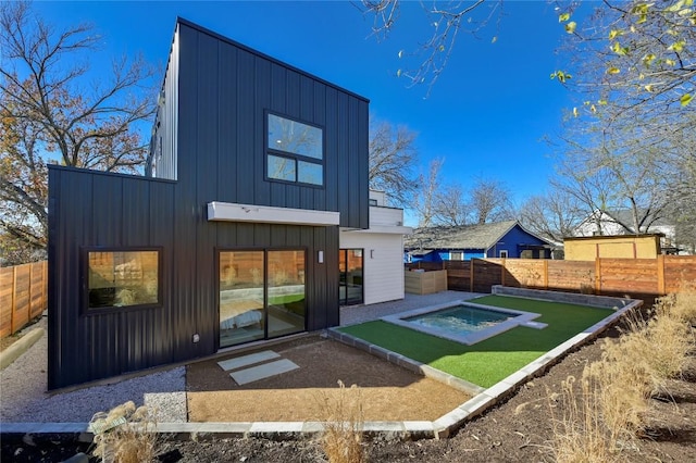 rear view of property featuring board and batten siding and a fenced backyard