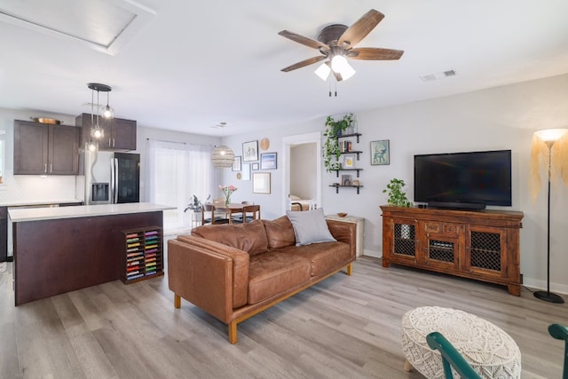 living room featuring ceiling fan, visible vents, and light wood finished floors