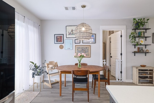 dining area featuring an inviting chandelier, baseboards, light wood-type flooring, and visible vents