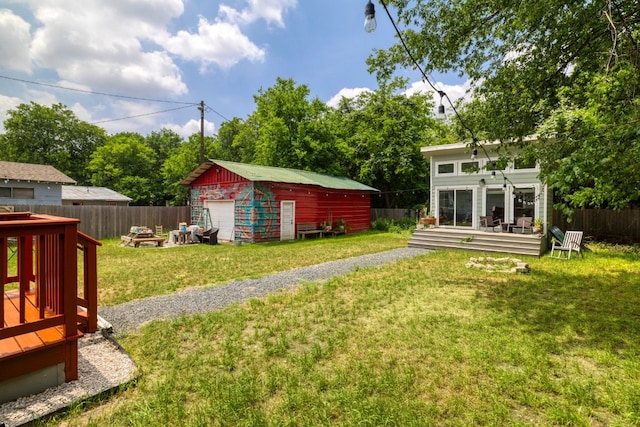 view of yard with an outdoor structure, a fenced backyard, a garage, and a wooden deck