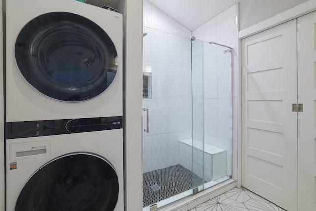full bath featuring tile patterned flooring, a shower stall, and stacked washer and clothes dryer