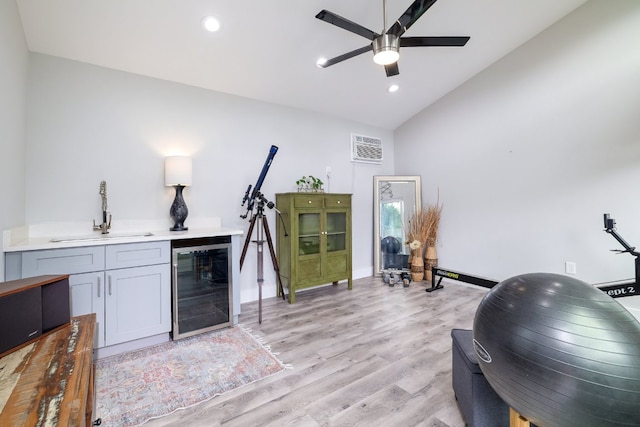 interior space featuring lofted ceiling, beverage cooler, indoor bar, light wood-type flooring, and a sink