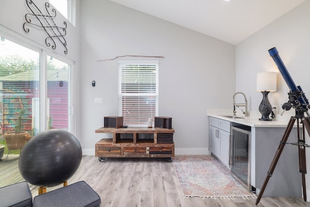 bar with a sink, a wealth of natural light, light wood-type flooring, and wine cooler