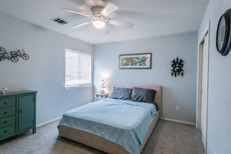 bedroom with a ceiling fan, baseboards, visible vents, and carpet