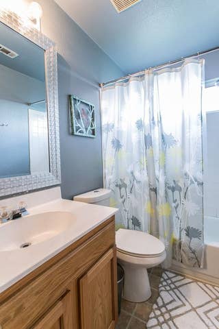 bathroom featuring tile patterned flooring, vanity, toilet, shower / bath combination with curtain, and visible vents