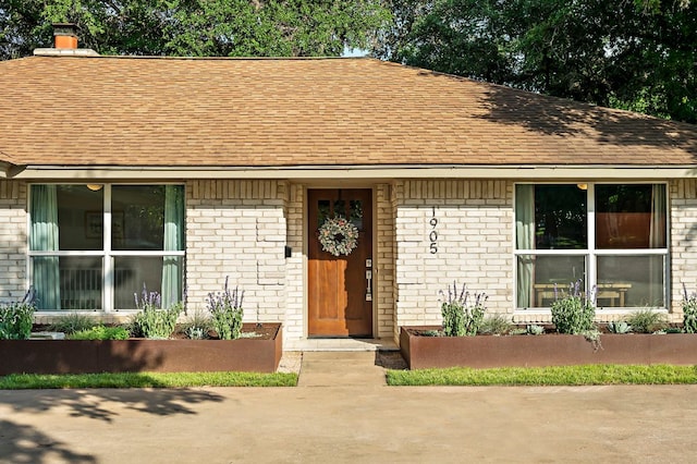 view of front of house with brick siding and roof with shingles