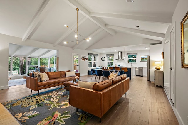 living area featuring a chandelier, baseboards, lofted ceiling with beams, and light wood-style flooring