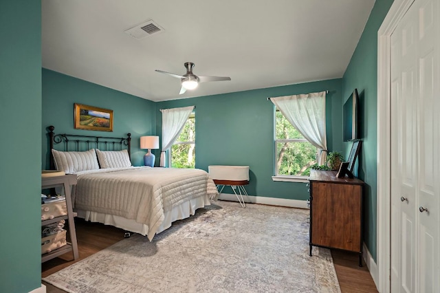bedroom featuring baseboards, a ceiling fan, wood finished floors, and visible vents