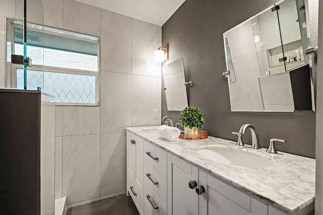 full bath with double vanity, a sink, walk in shower, and tile patterned flooring