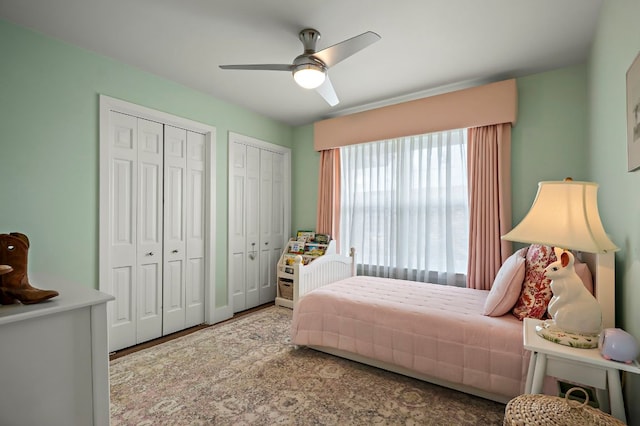 bedroom with ceiling fan, multiple closets, and wood finished floors