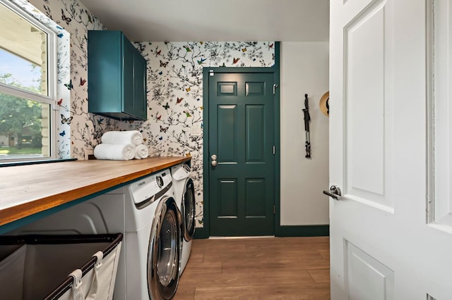 washroom featuring separate washer and dryer, laundry area, wood finished floors, and wallpapered walls