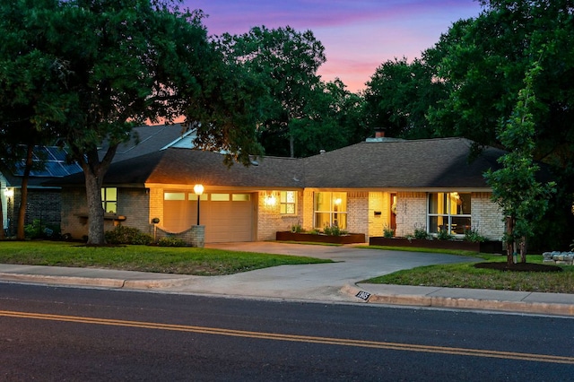 ranch-style home featuring an attached garage, driveway, and brick siding