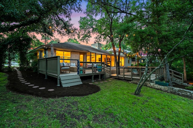 back of house with a lawn, a deck, and a chimney