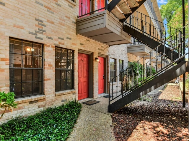 doorway to property with a balcony and stone siding