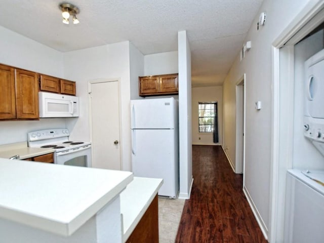 kitchen with brown cabinets, white appliances, light countertops, a peninsula, and dark wood-type flooring