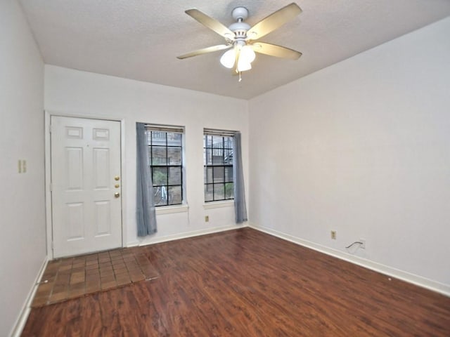 interior space with baseboards, a textured ceiling, ceiling fan, and wood finished floors