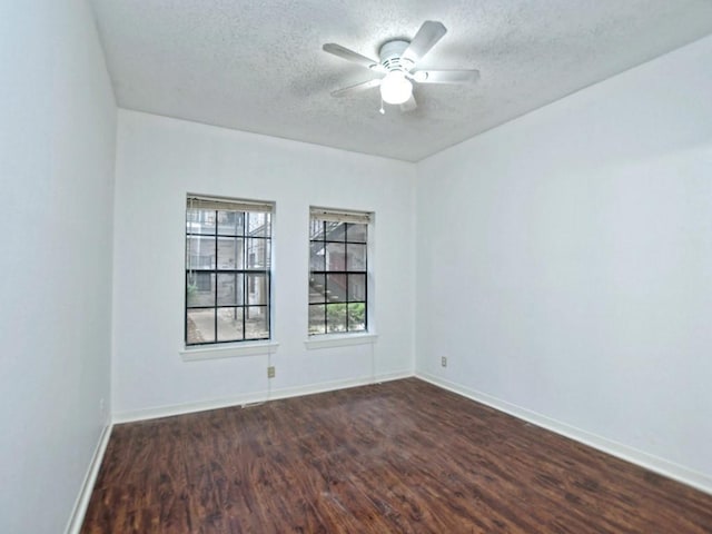 spare room featuring a textured ceiling, baseboards, and dark wood-type flooring