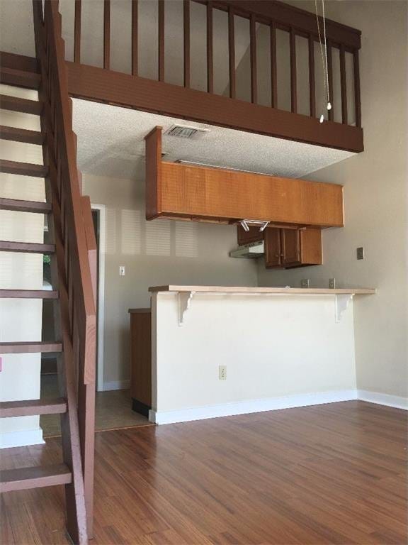 kitchen with brown cabinets, a breakfast bar, baseboards, dark wood-type flooring, and visible vents
