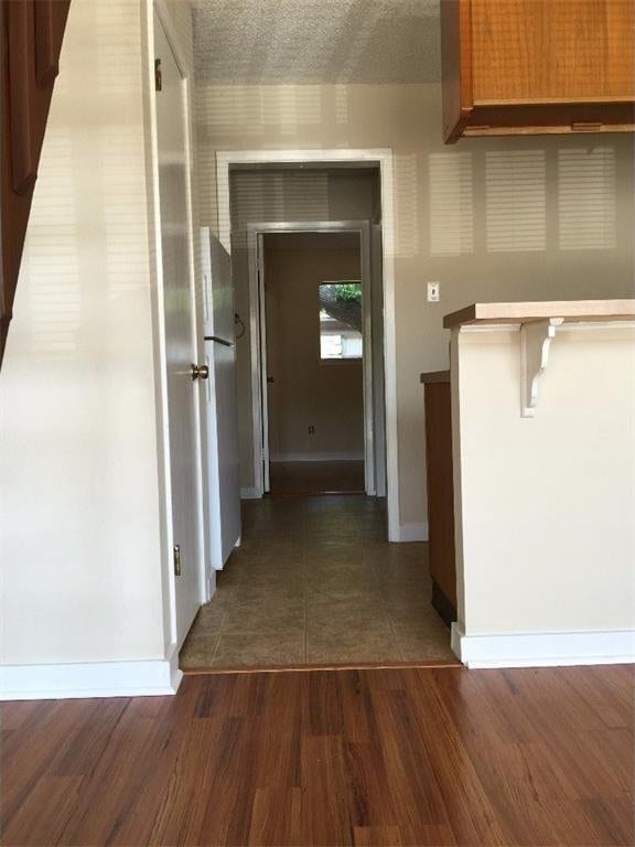 hall featuring baseboards and dark wood-type flooring