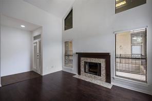 unfurnished living room featuring a tiled fireplace, a high ceiling, and wood finished floors