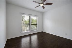 empty room with baseboards, a ceiling fan, and dark wood finished floors