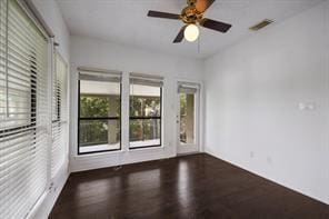 empty room with visible vents, a ceiling fan, and wood finished floors