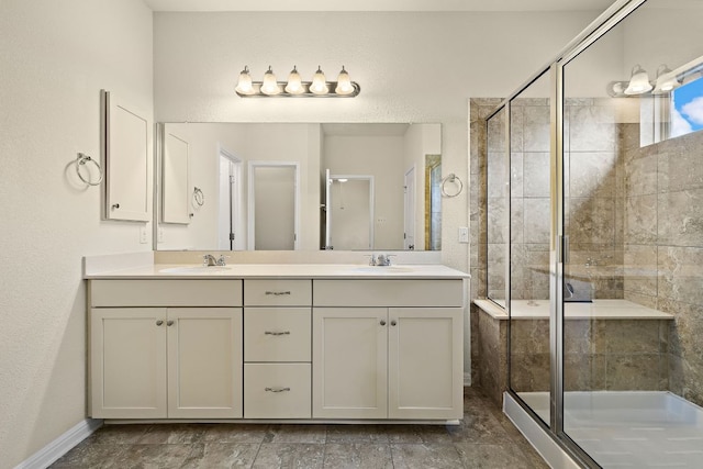 bathroom with double vanity, a sink, baseboards, and a stall shower