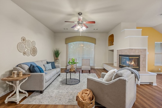 living room featuring a ceiling fan, baseboards, wood finished floors, and a fireplace
