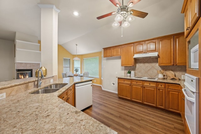 kitchen featuring light stone counters, a sink, white appliances, under cabinet range hood, and vaulted ceiling