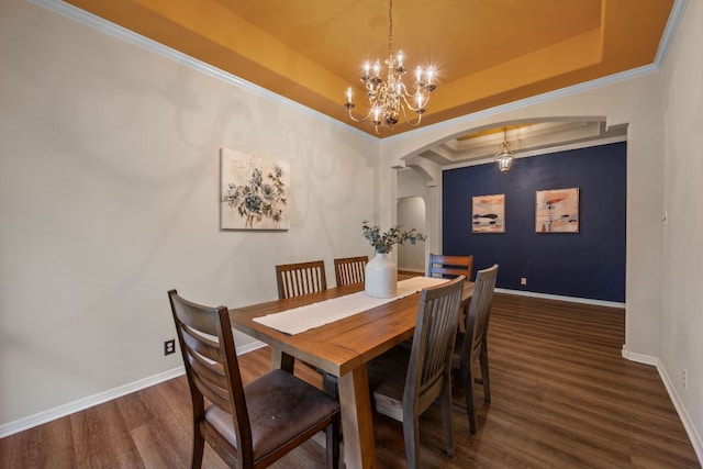 dining area featuring arched walkways, wood finished floors, baseboards, a raised ceiling, and an inviting chandelier