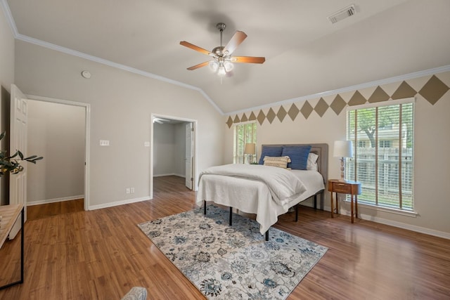 bedroom with crown molding, baseboards, lofted ceiling, and wood finished floors