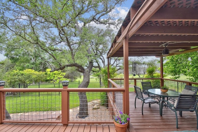 wooden terrace with a yard, ceiling fan, fence, and outdoor dining area