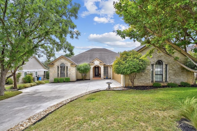 view of front facade with a front yard, driveway, stone siding, and a garage