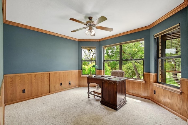 carpeted office featuring wooden walls, ornamental molding, wainscoting, and ceiling fan