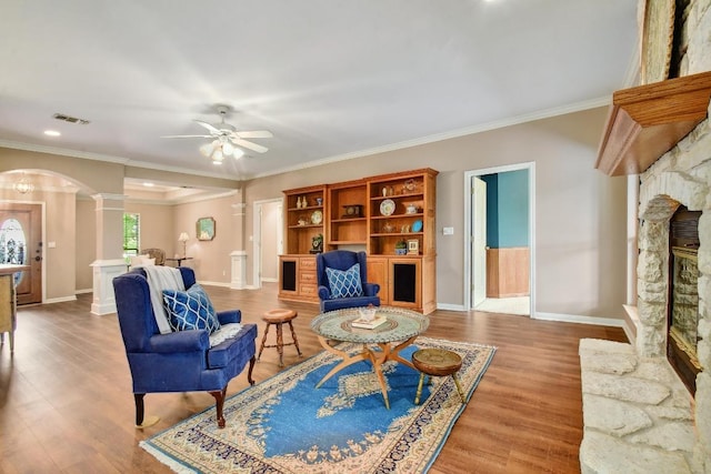 living area featuring ornate columns, arched walkways, baseboards, and visible vents