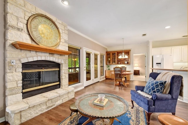 living room featuring a stone fireplace, ornamental molding, wood finished floors, and visible vents