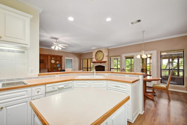 kitchen featuring visible vents, crown molding, dishwasher, a sink, and white cabinets