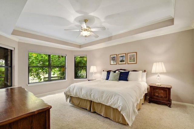 bedroom featuring crown molding, a tray ceiling, and light colored carpet