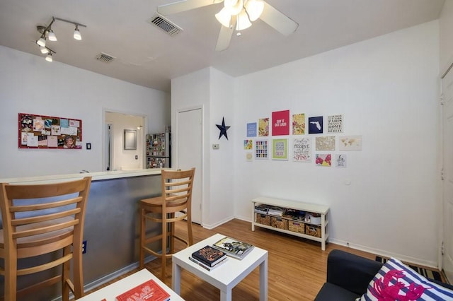 living area with a bar, ceiling fan, visible vents, and wood finished floors