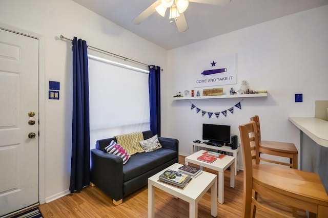living room featuring ceiling fan, baseboards, and light wood-style floors