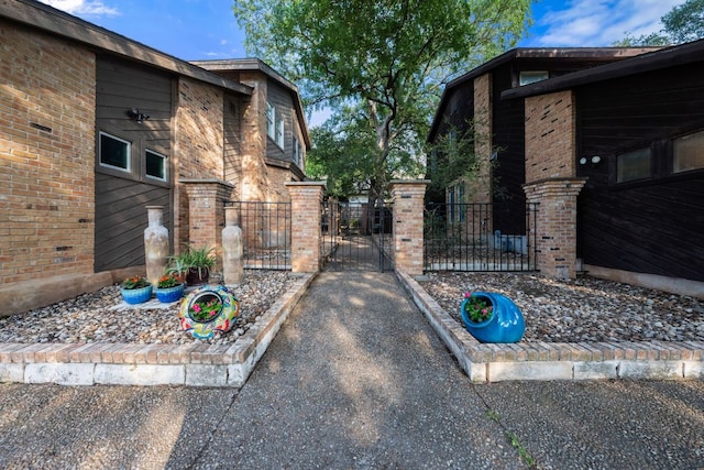 view of property exterior featuring brick siding, fence, and a gate