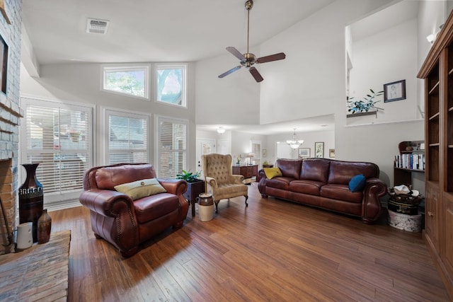living area featuring high vaulted ceiling, ceiling fan with notable chandelier, wood finished floors, and visible vents