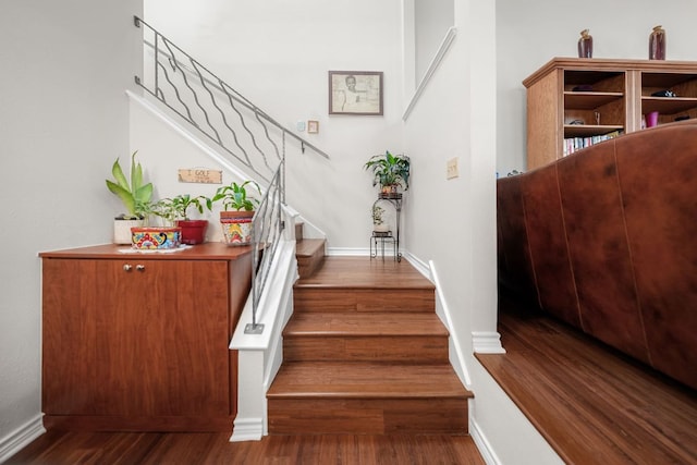 staircase featuring baseboards and wood finished floors